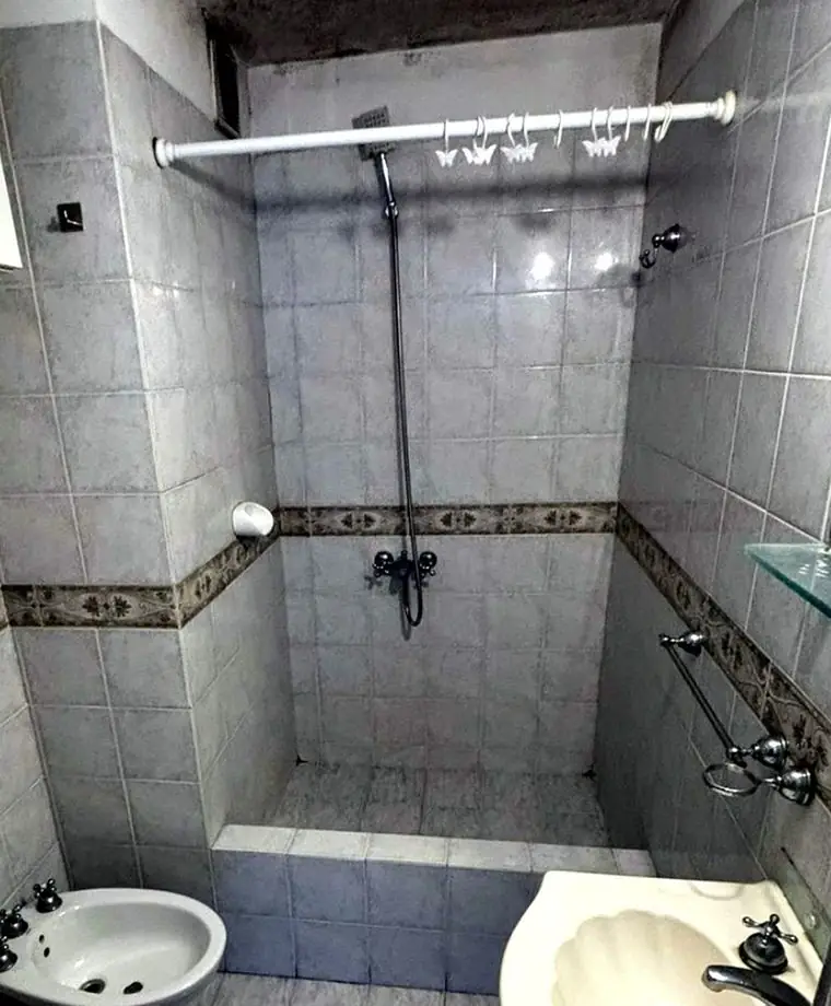 Baño original con azulejos antiguos y humedad en el cielorraso