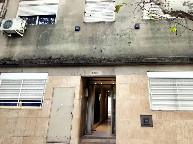 Frente de edificio con humedad y revoque deteriorado antes de la obra