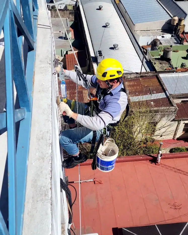 Operario suspendido reparando el muro exterior de un edificio