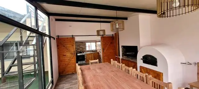Parrilla, horno de barro y puertas corredizas de madera en el quincho