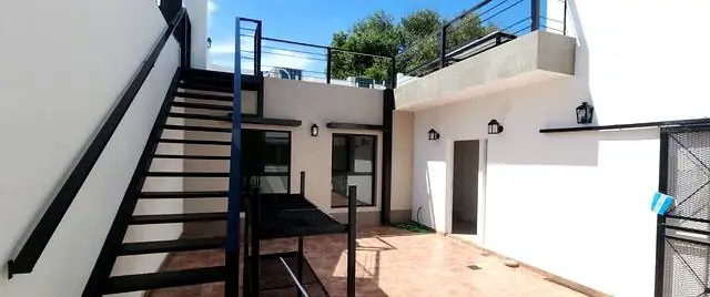 Patio terminado con escalera metálica y aberturas de aluminio negro